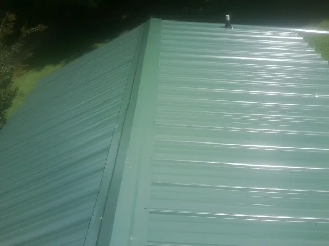 New green metal panels meeting at the ridge of a roof — Flat Roof Repair work by our crew in Satsop