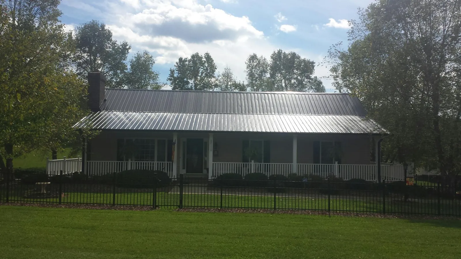 Gray metal roof on a brick ranch with a full width front porch — Gutter Guard Installation work by our crew in Satsop
