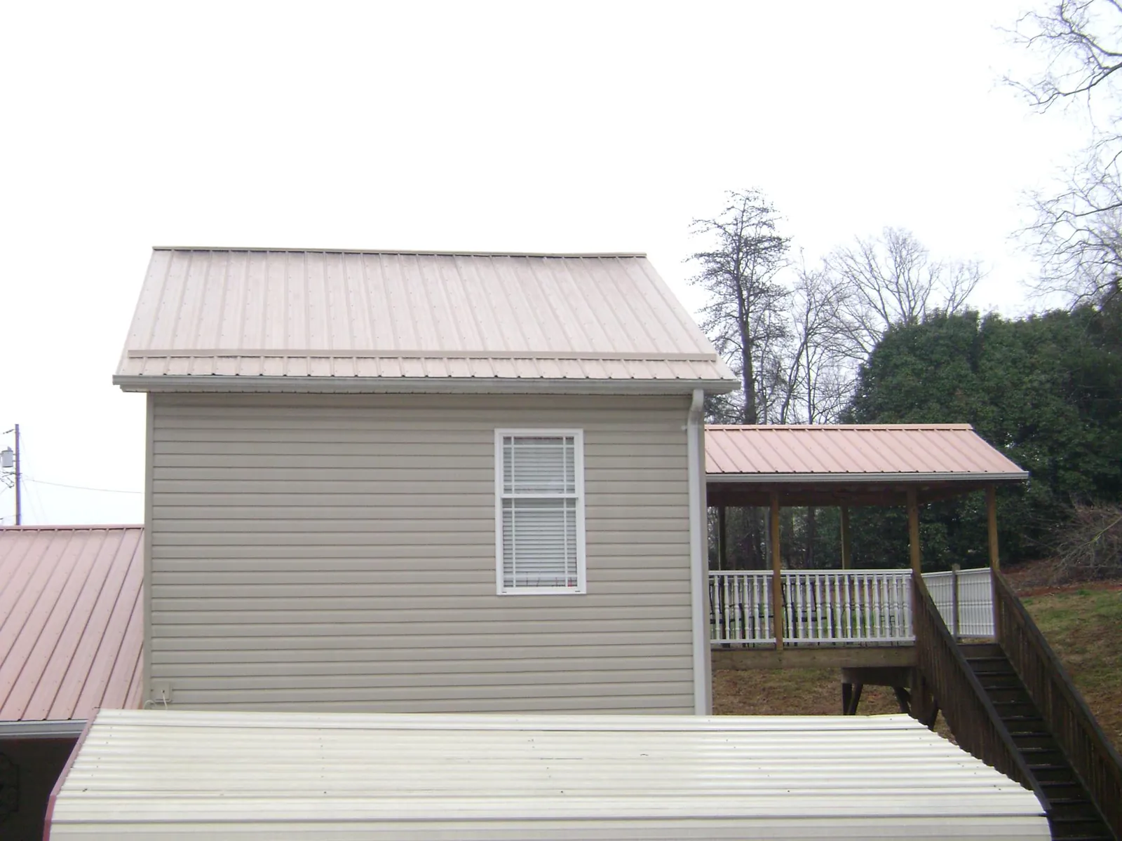 Tan metal roofs on a two story addition and attached porch, from a Roof Replacement job in Satsop