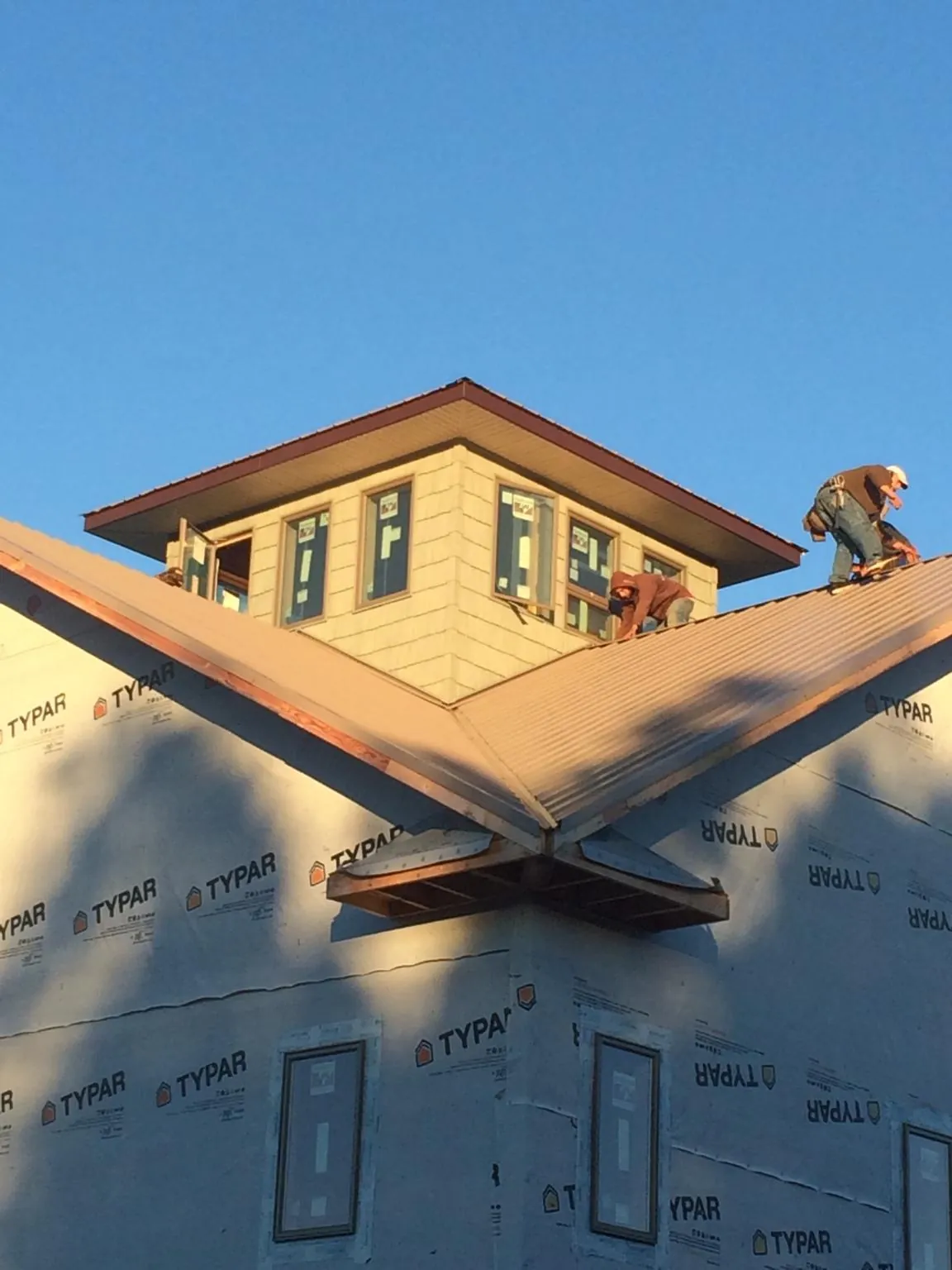Roofers working around a rooftop cupola on a new metal roof at sunset — Roof Waterproofing in Satsop by Roofing Brothers
